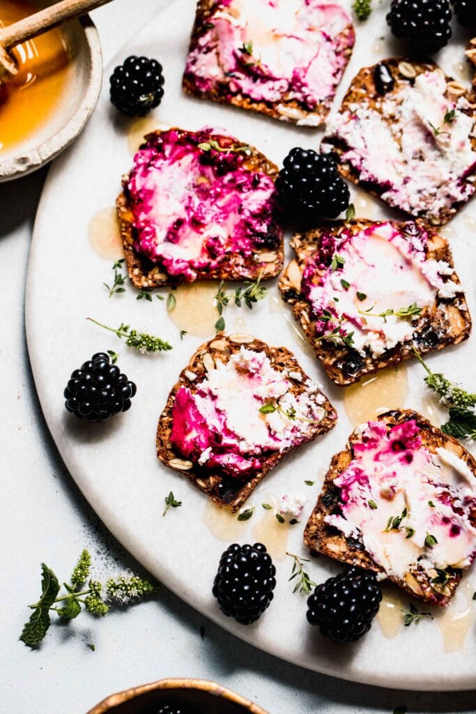 Crackers spread with blackberry goat cheese on serving platter.