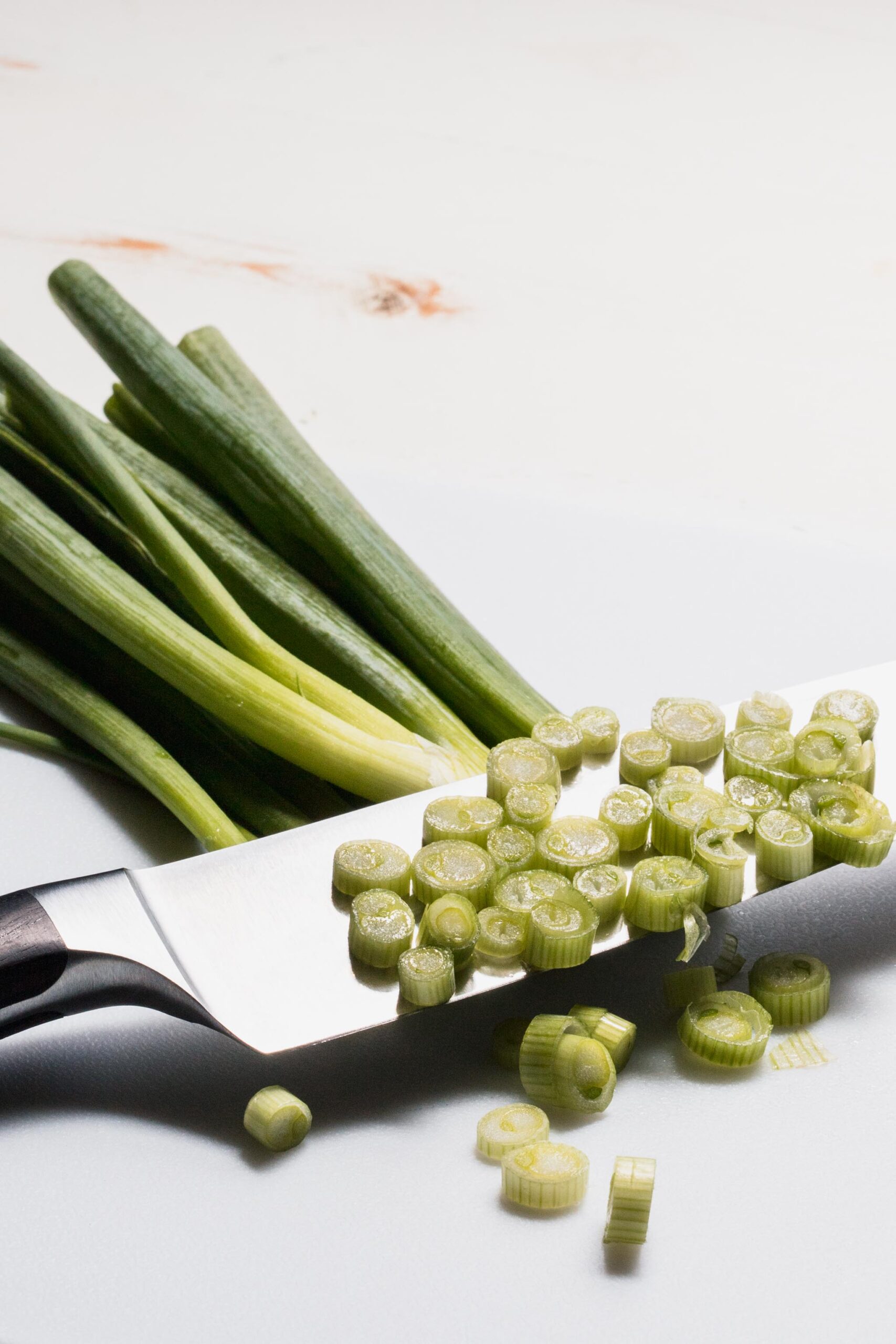 Knife cut through green onions to make circular cuts. 