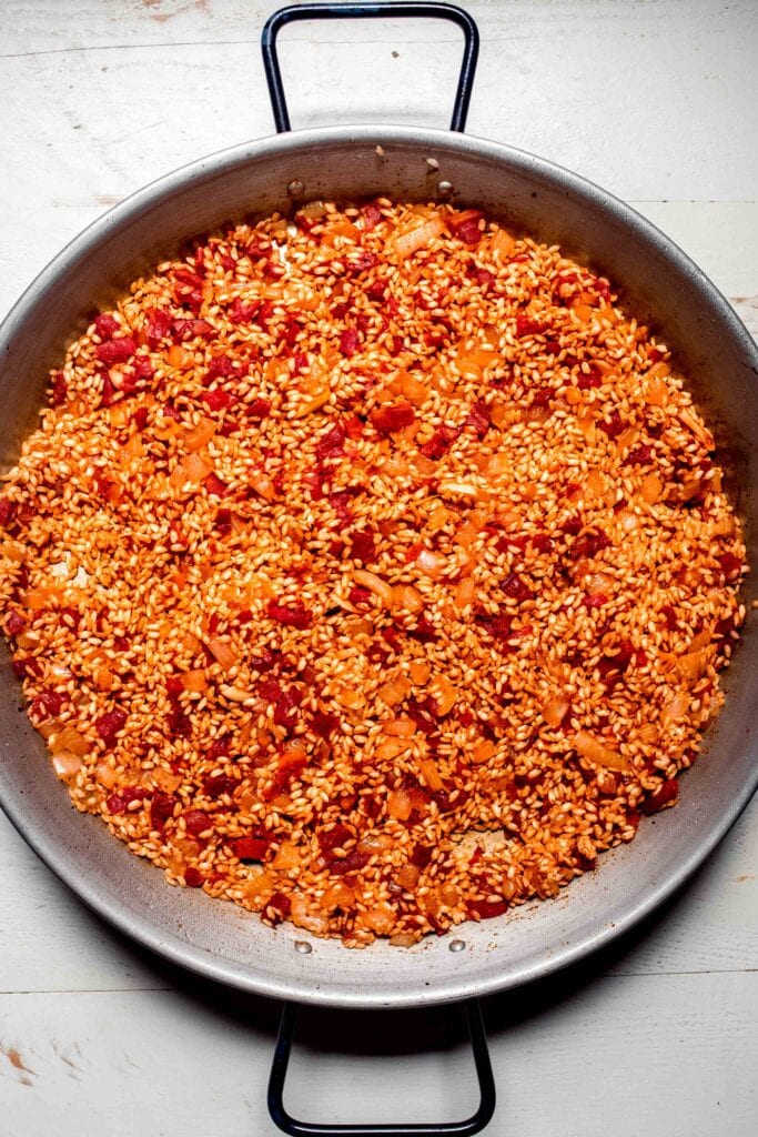 Toasted rice in paella pan. 