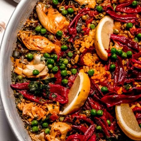 Overhead close up of veggie paella topped with lemons.