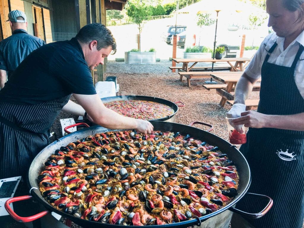 Men making paella in giant pans. 