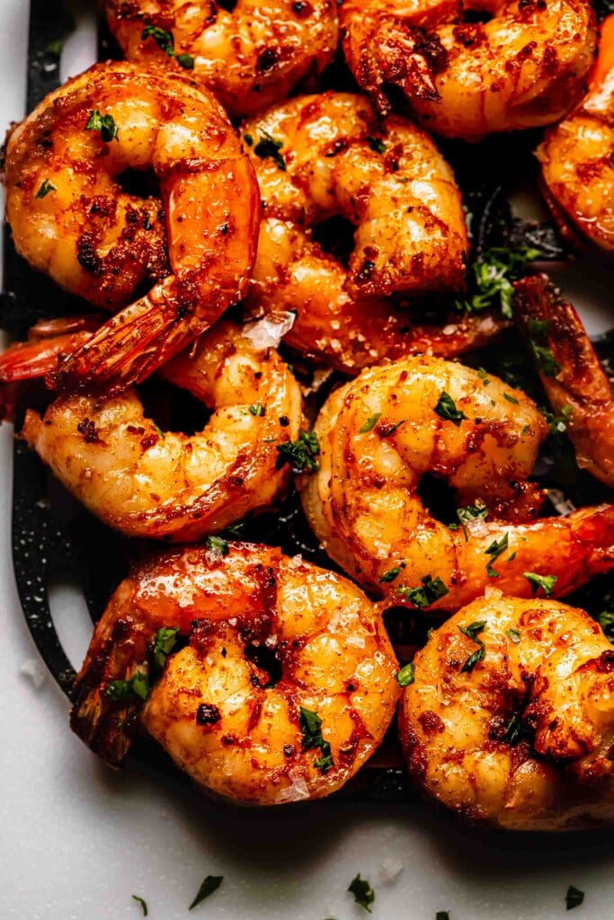 Overhead close up of cooked shrimp on air fryer basket liner. 