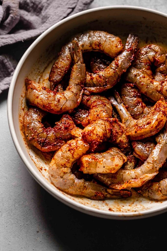 Shrimp in bowl tossed with spices.