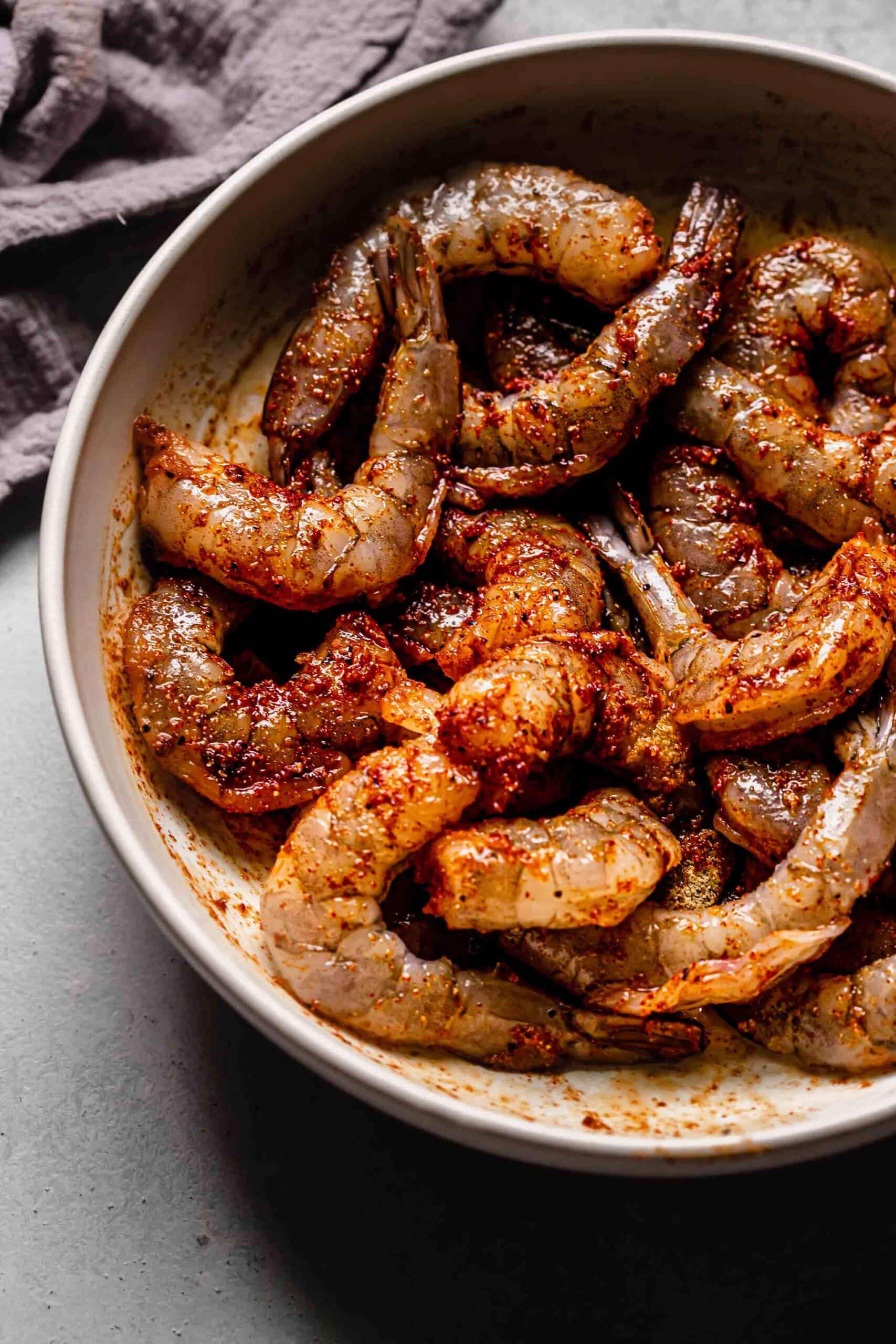 Shrimp in bowl tossed with spices. 