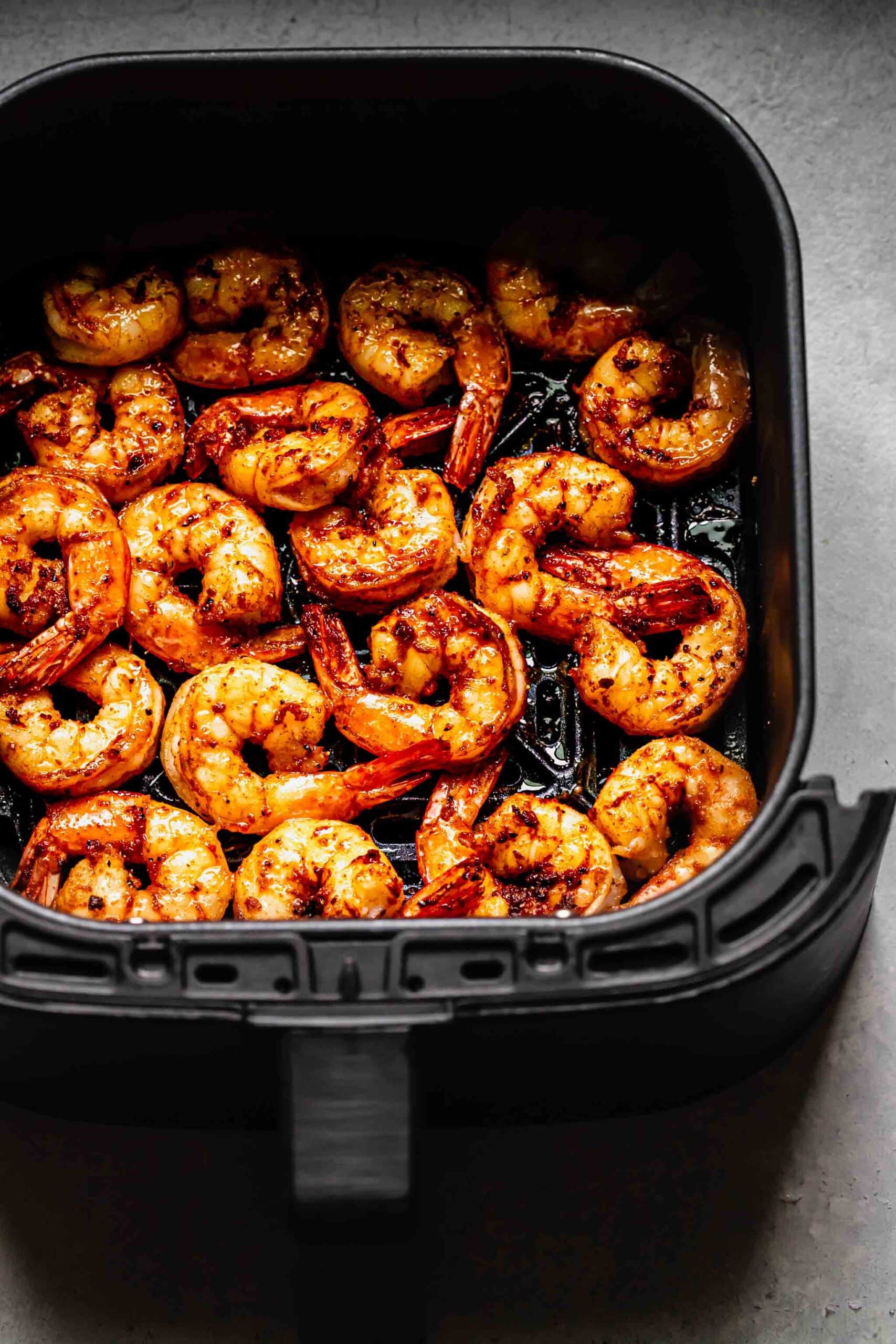 Cooked shrimp in air fryer basket. 