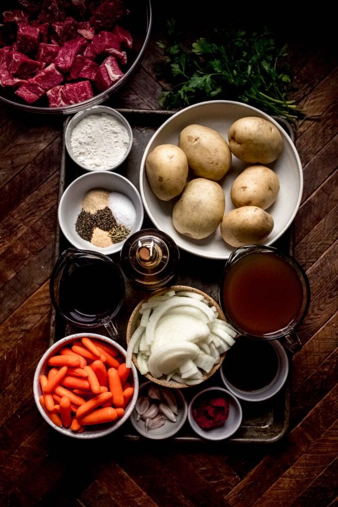 Ingredients for beef stew on wood counter. 