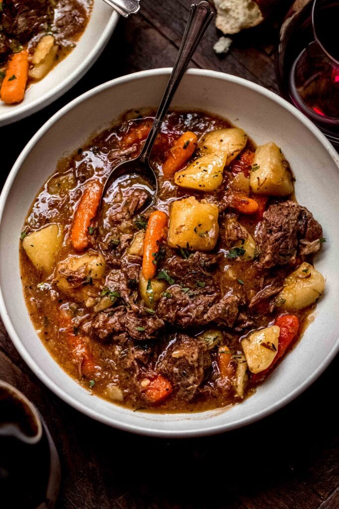 Overhead shot of beef stew in bowl on wood background.