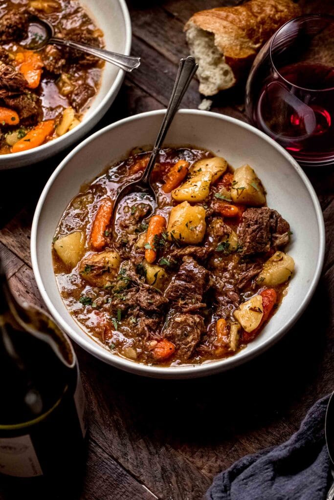 Side view of beef stew in white bowl with spoon.