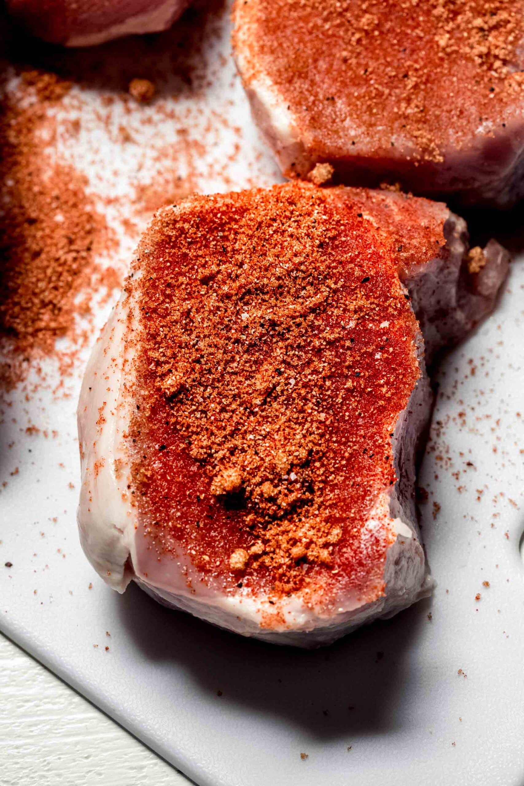 Uncooked Pork chop sprinkled with seasonings.
