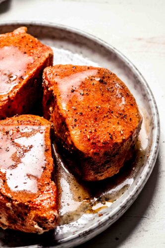 Cooked pork chops on plate with gravy.