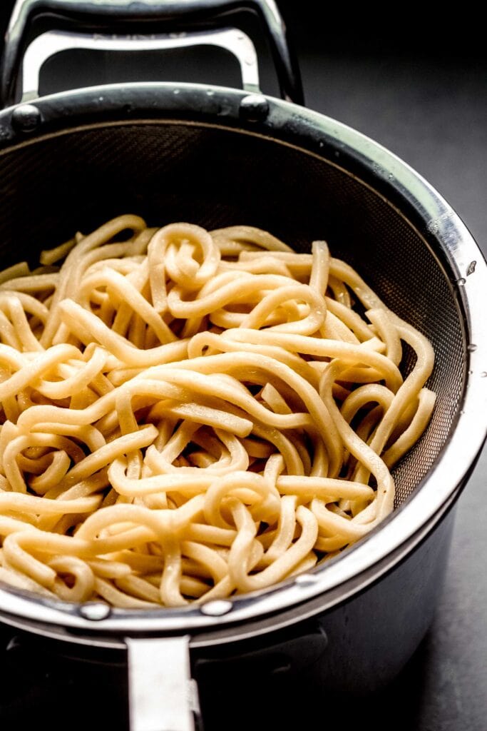 Drained udon noodles in colander.