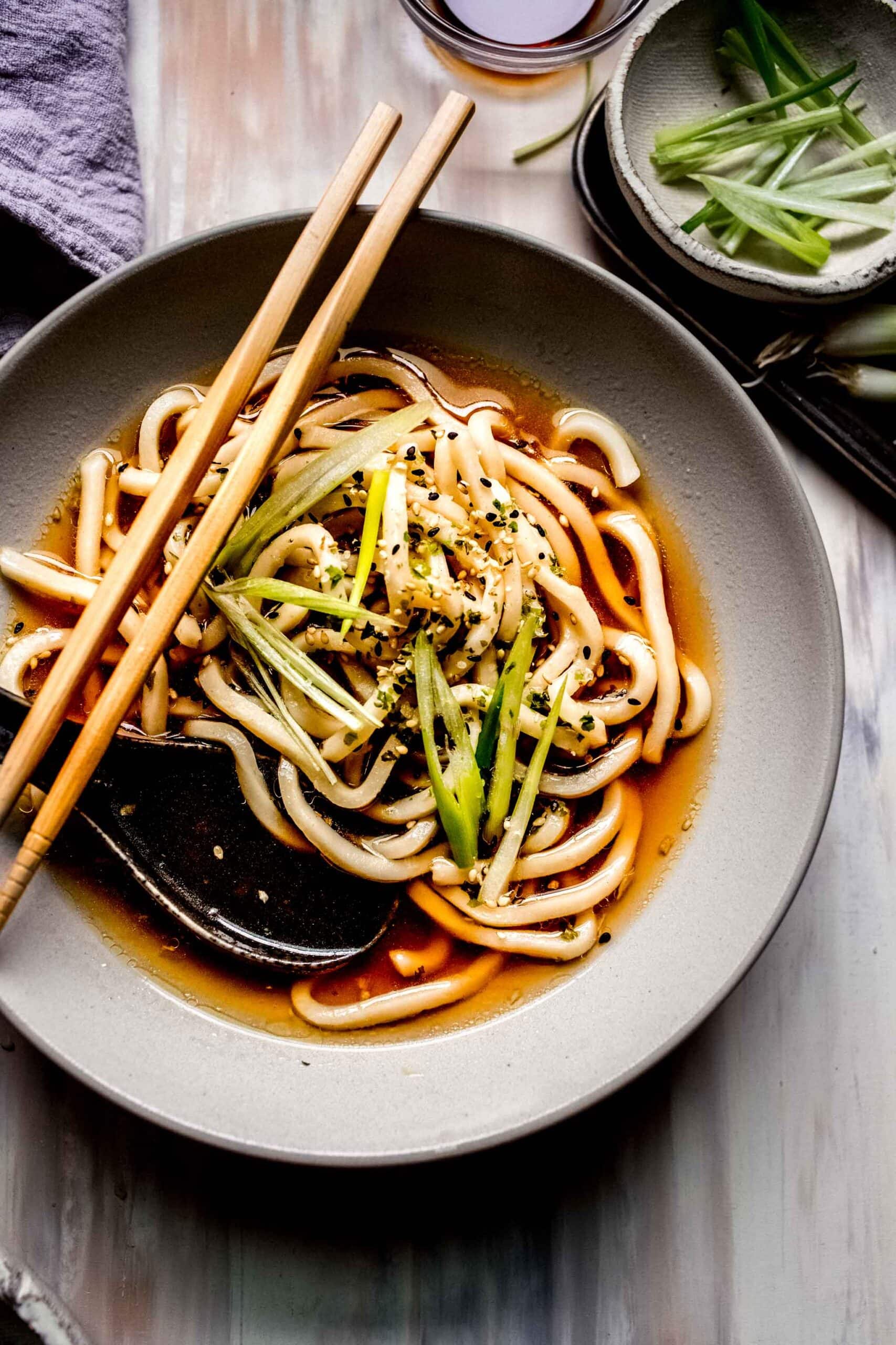 Overhead shot of bowl of udon soup with soup spoon and chopsticks.