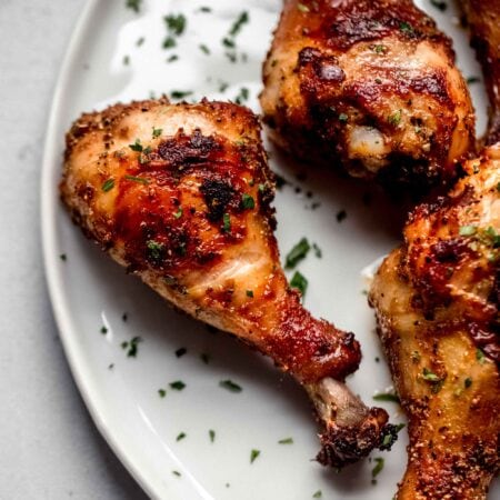 Crispy chicken air fryer drumsticks on white plate.