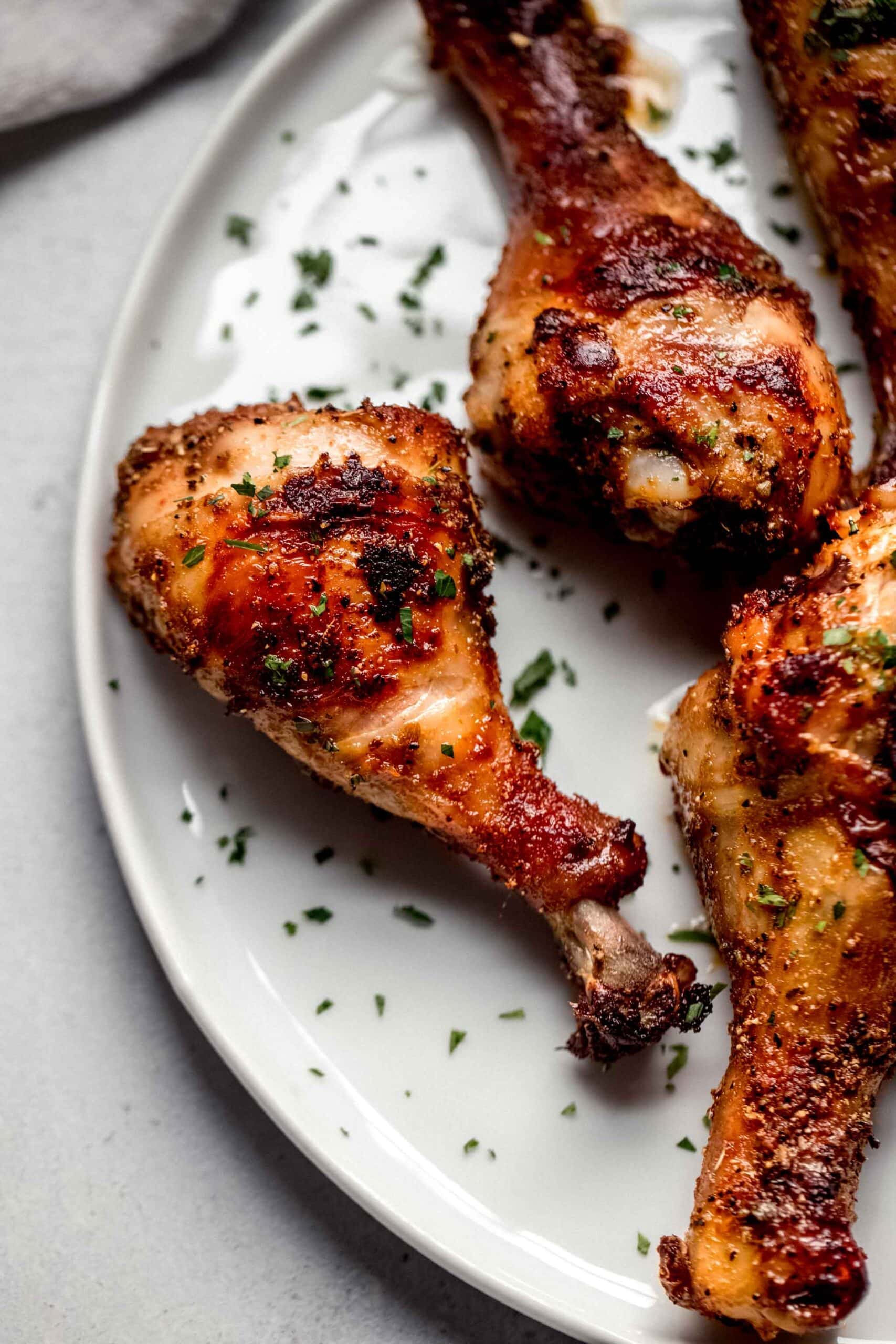 Crispy chicken air fryer drumsticks on white plate.