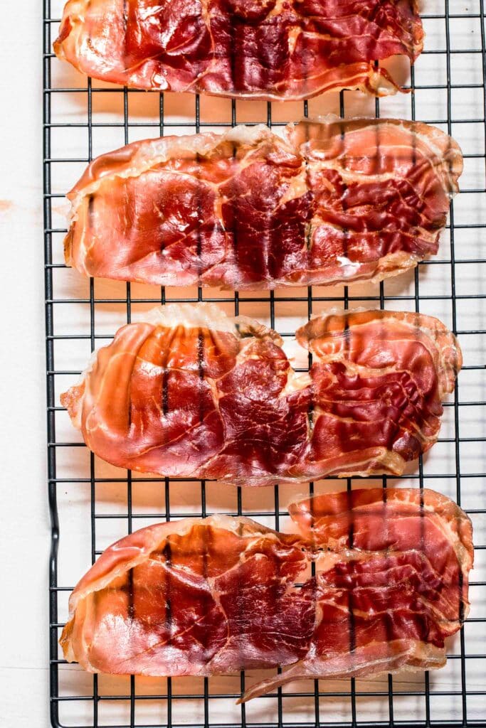 Slices of crispy prosciutto on cooling rack.