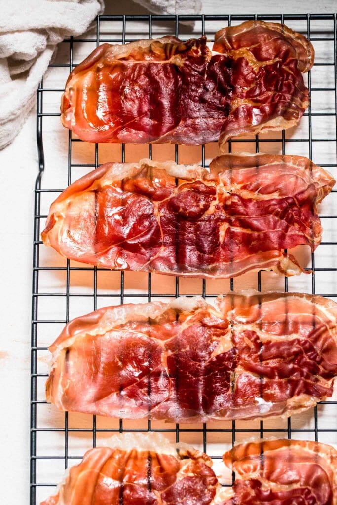 Slices of crispy prosciutto on cooling rack.