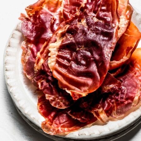Crispy prosciutto stacked on serving plate.