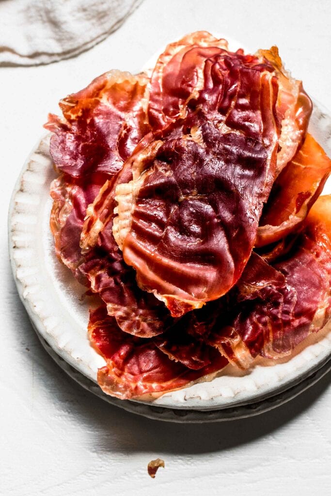 Crispy prosciutto stacked on serving plate. 