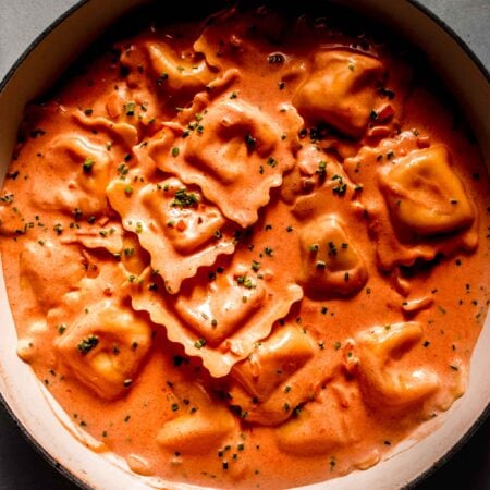 Lobster ravioli in skillet tossed with cream sauce and topped with chives.