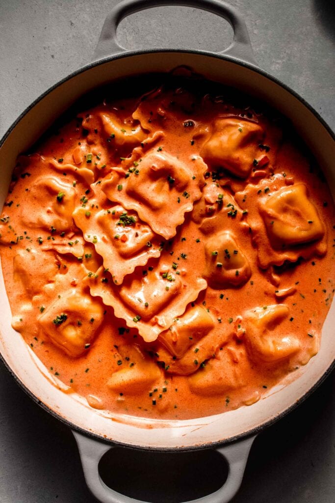 Lobster ravioli in skillet tossed with cream sauce and topped with chives. 