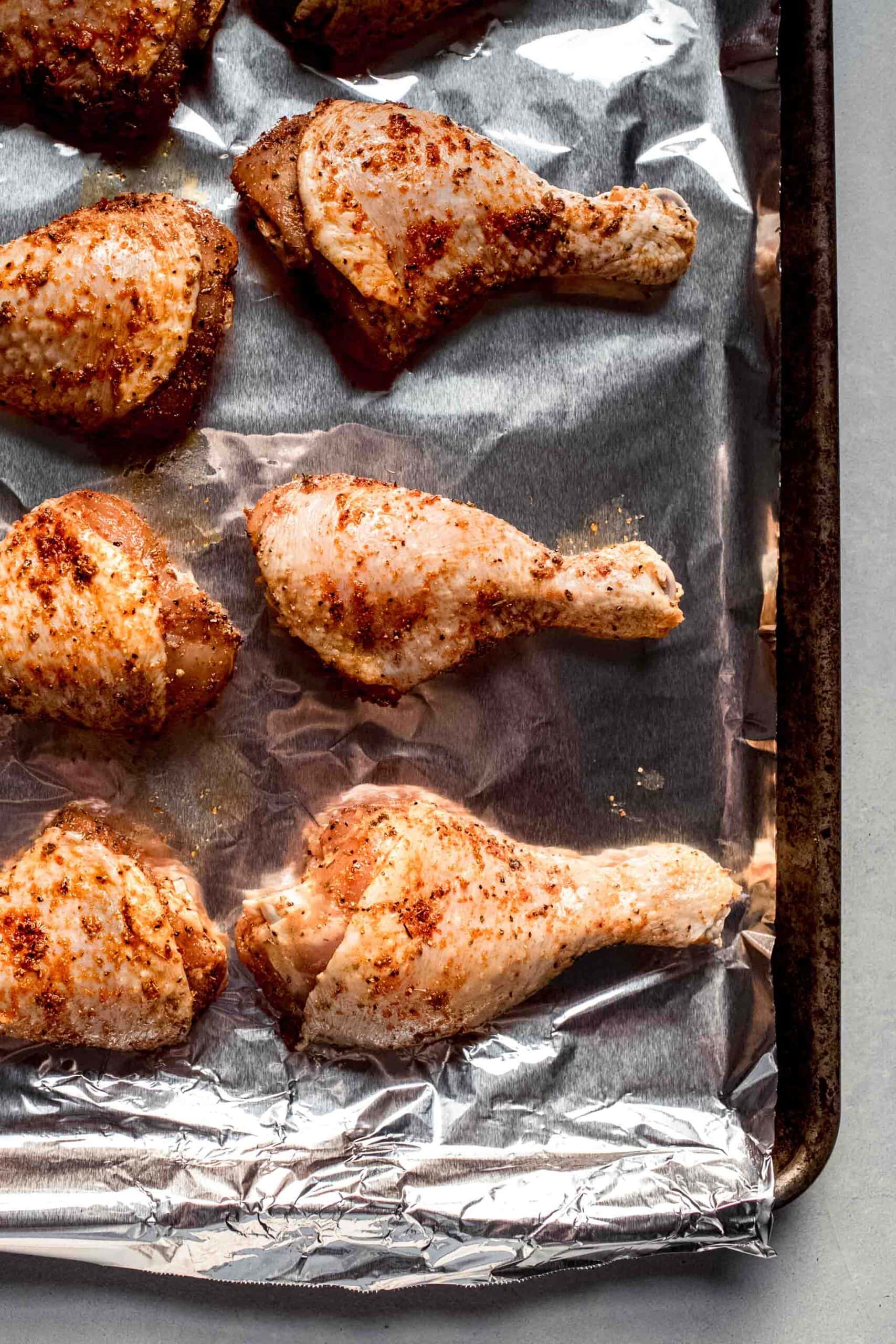 Uncooked chicken legs on baking sheet. 