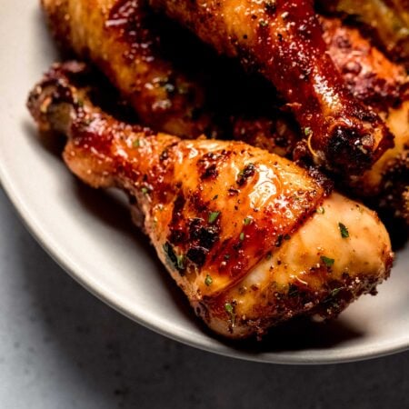 Baked chicken legs in white serving bowl.