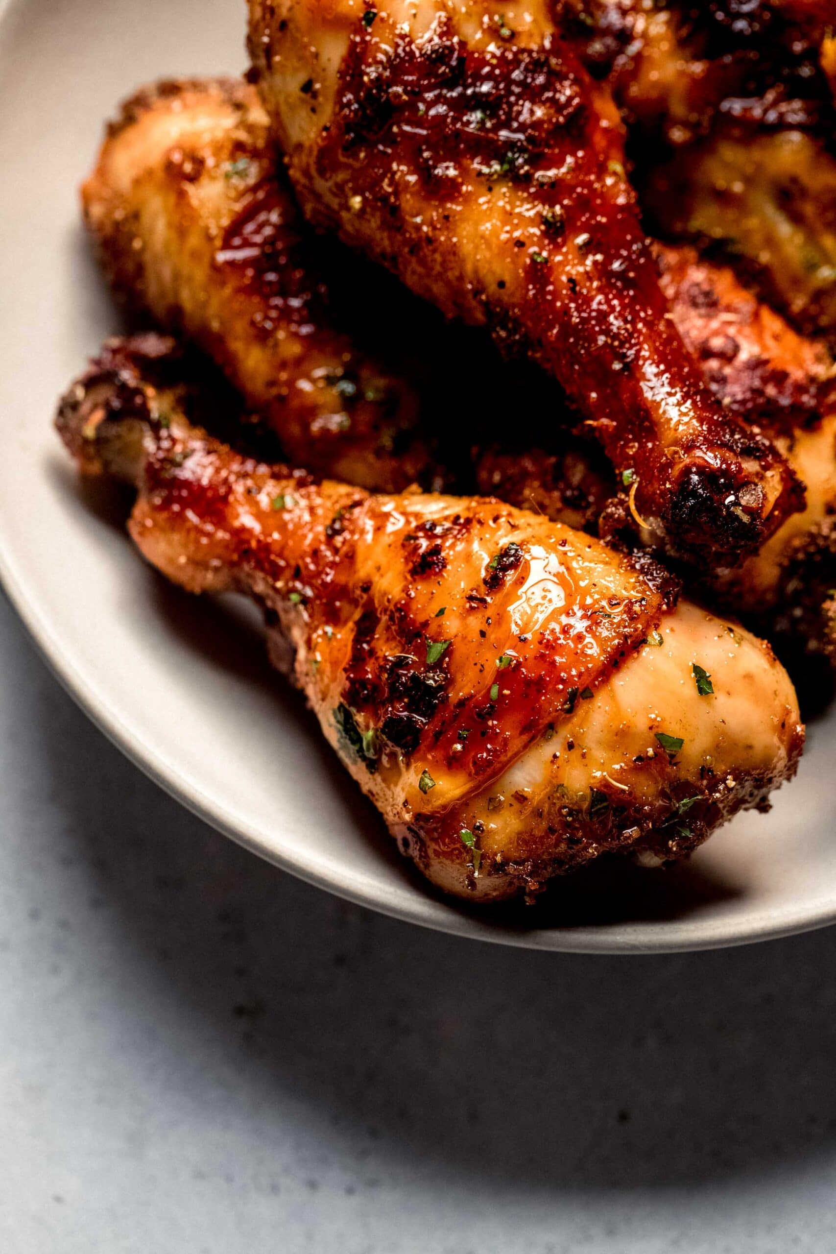 Baked chicken legs in white serving bowl.