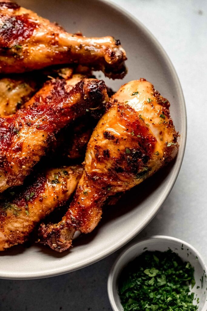 Oven baked chicken legs piled in serving bowl.