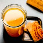 Overhead shot of jar of parmesan broth on small tray next to parm rinds.