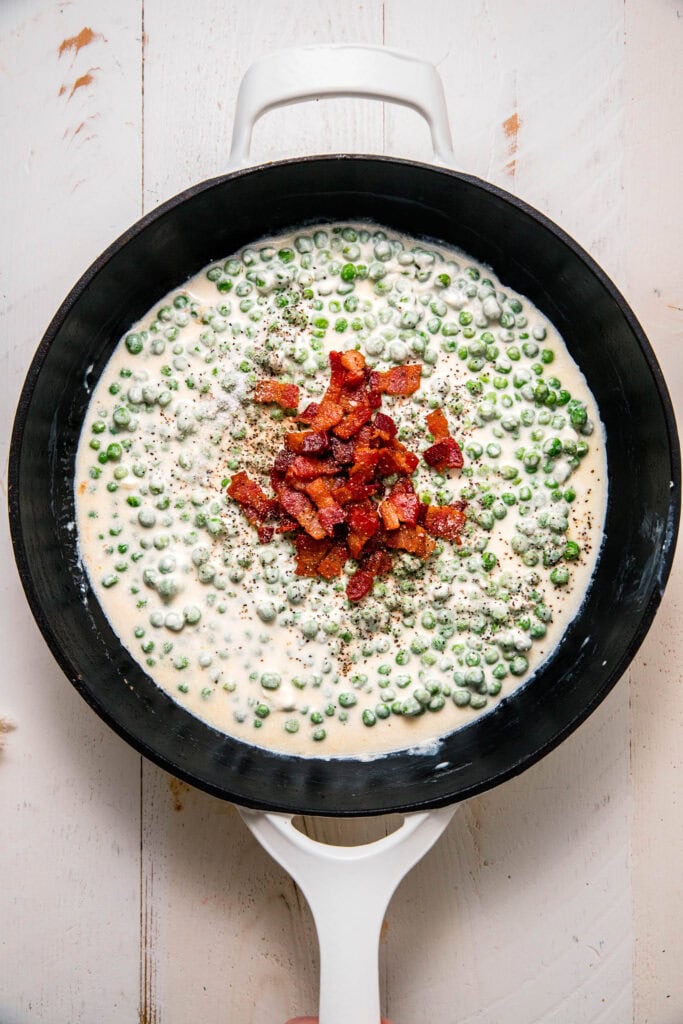 Bacon added to skillet with cream and peas.
