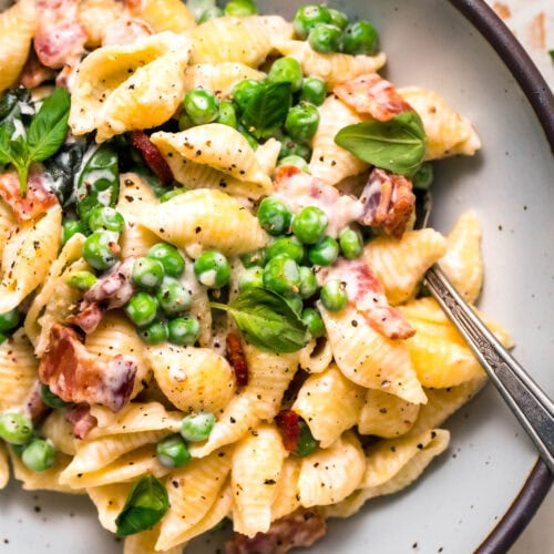Overhead close up of finished pea and bacon pasta in serving bowl.