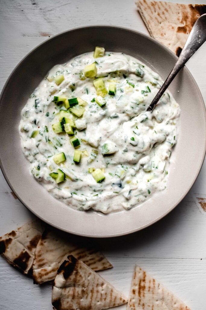 Raita sauce in bowl with serving spoon.