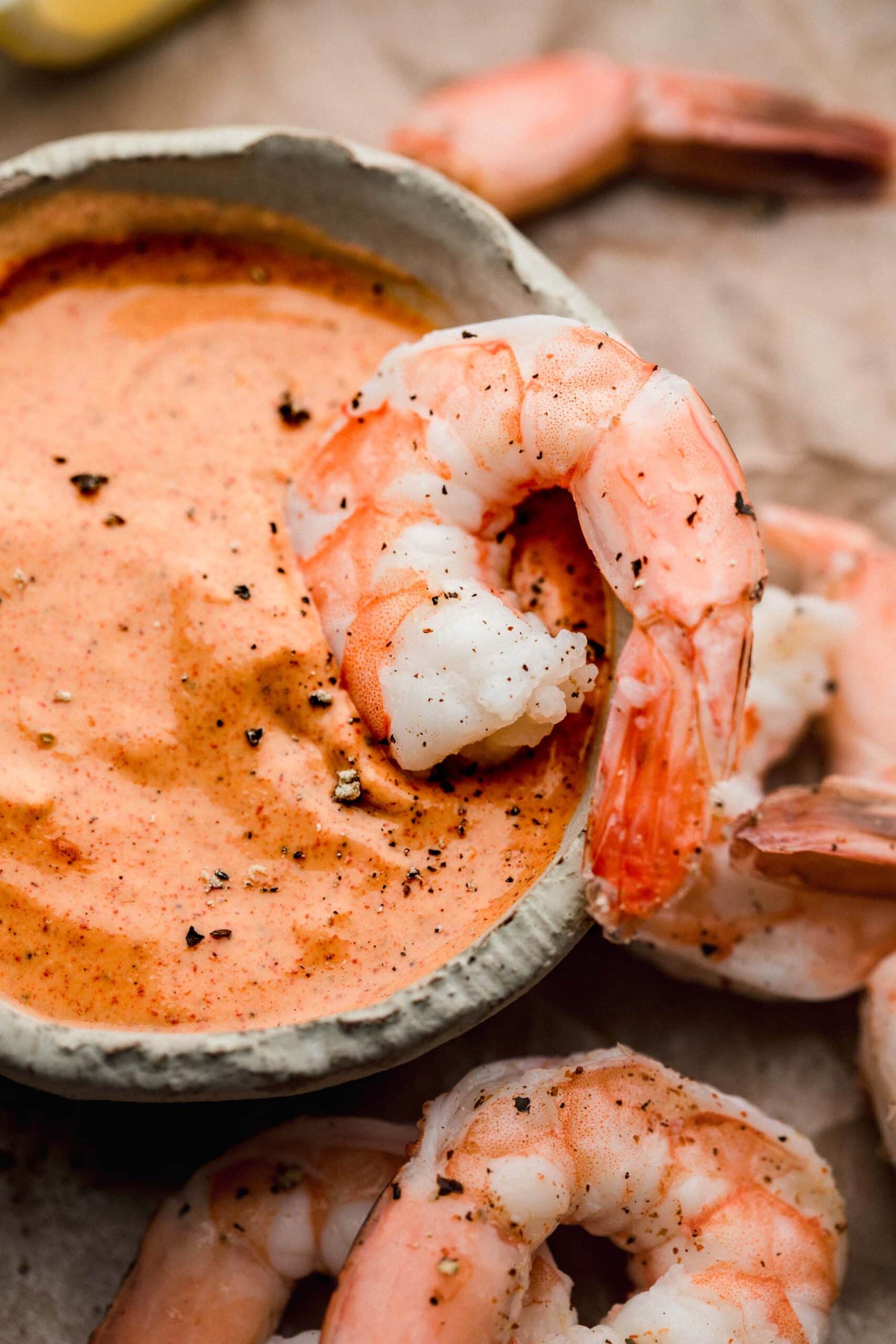 Shrimp being dipped into bowl of remoulade sauce.