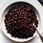 Black beans in white bowl with spoon.