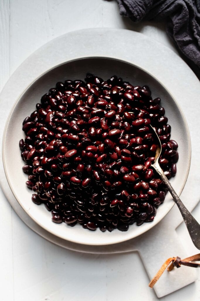 Black beans in white bowl with spoon.