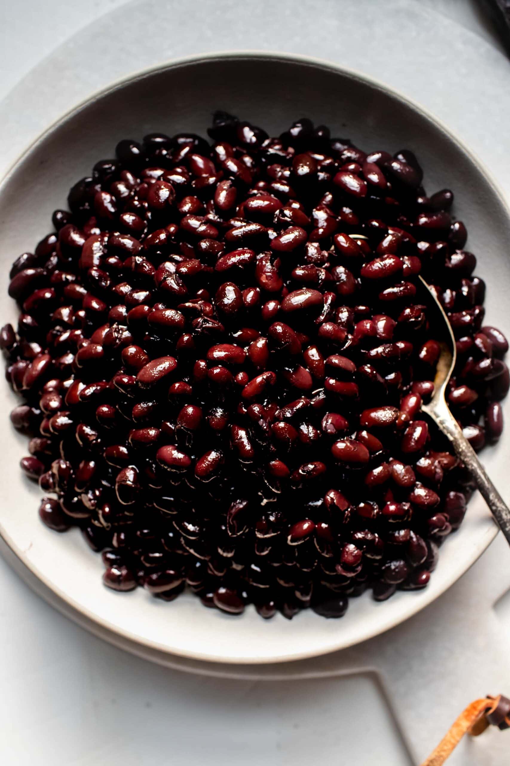 Black beans in white bowl with spoon.