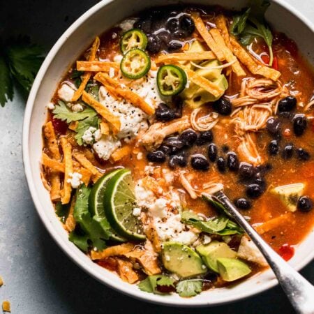 Overhead close up of bowl of slow cooker chicken tortilla soup in bowl with toppings.