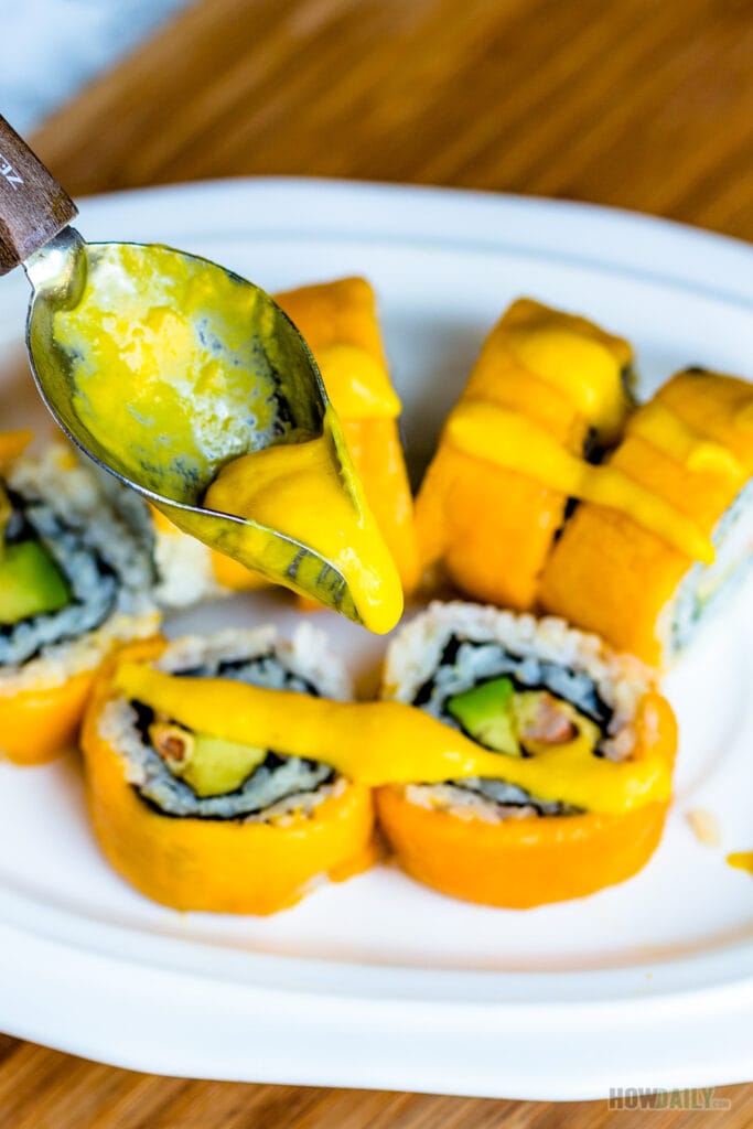 Mango sauce being drizzled on sushi.