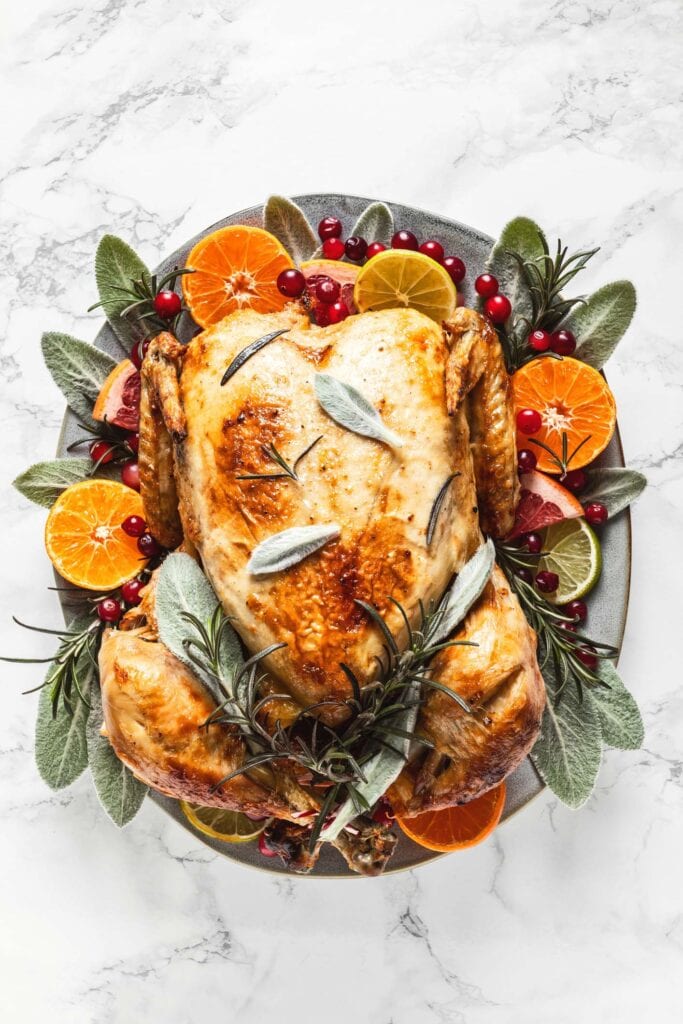 Thanksgiving turkey on platter with herbs and oranges. 