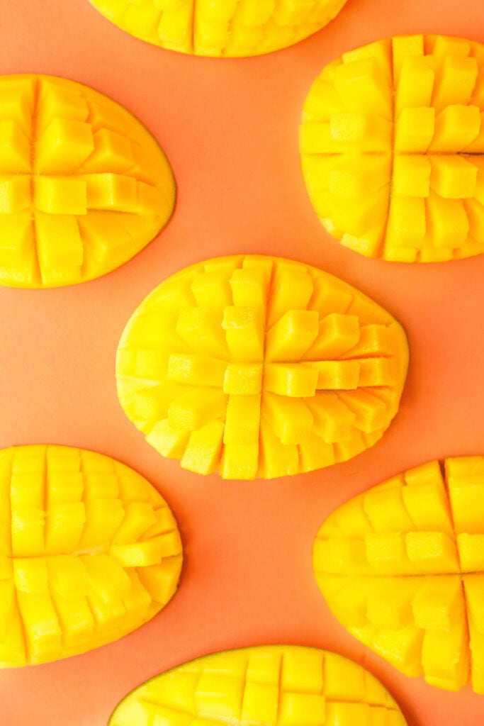 sliced mangoes on bright orange background. 