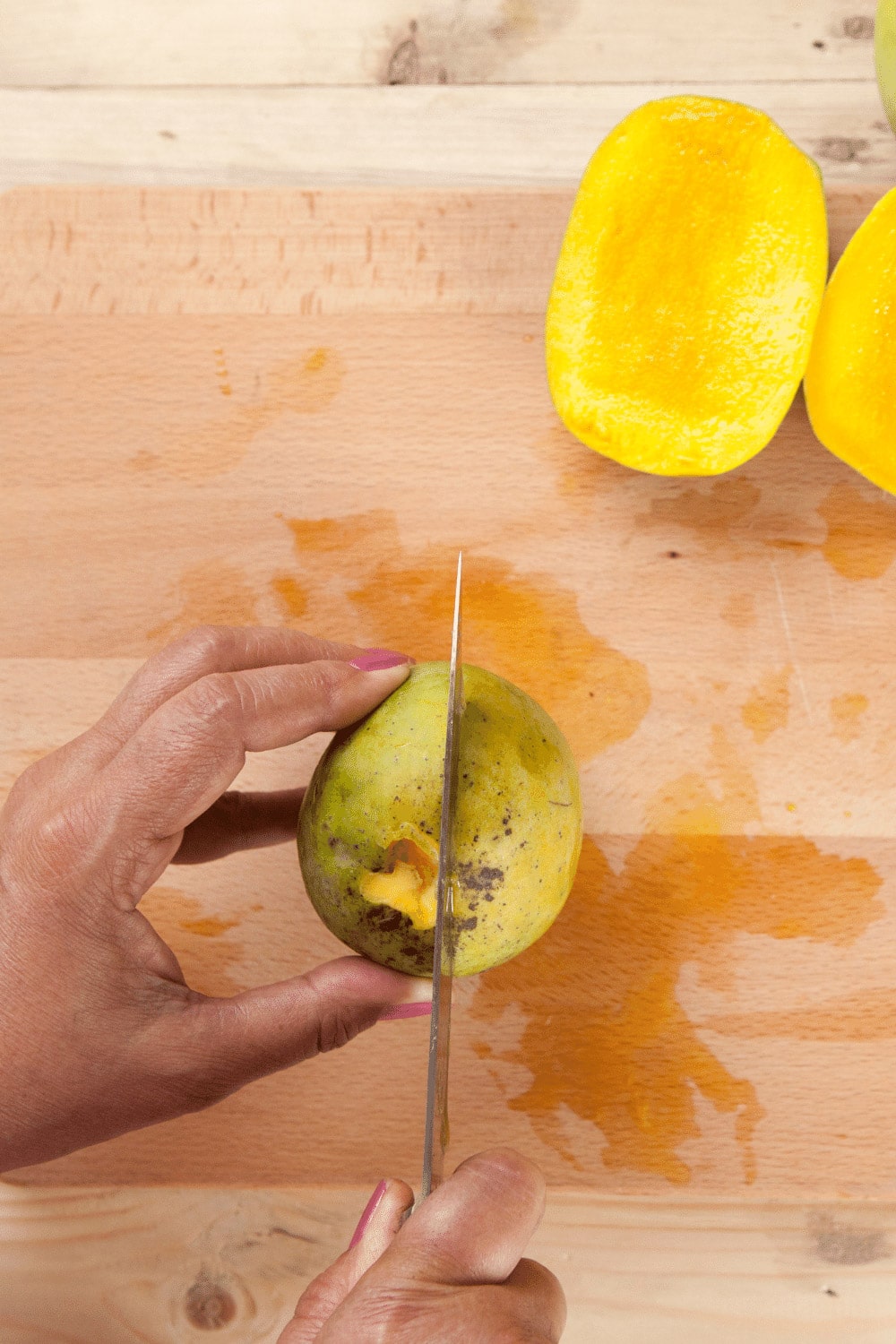 Hand slicing into mango. 
