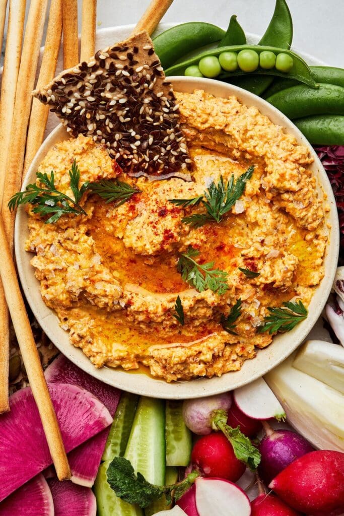 Carrot dip surrounded by veggies.