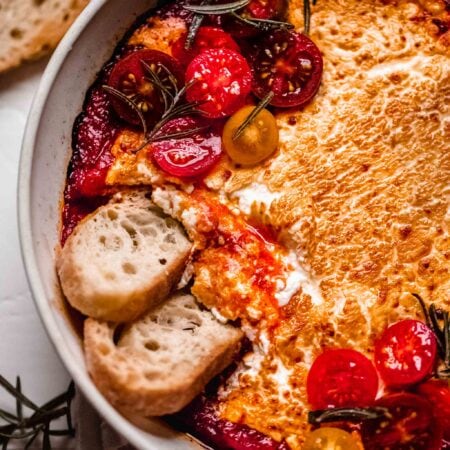 Baked goat cheese with marinara in dish.