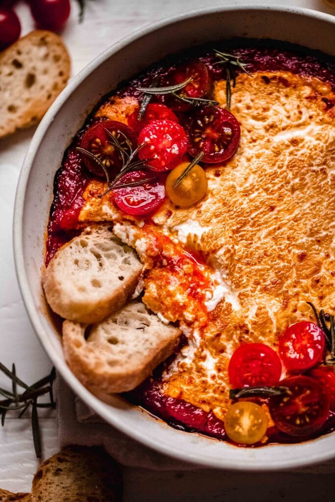 Baked goat cheese with marinara in dish.