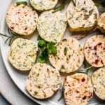 Pats of compound butter arranged on plate.