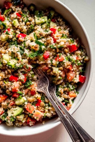 Copycat costco quinoa salad in white bowl with forks.