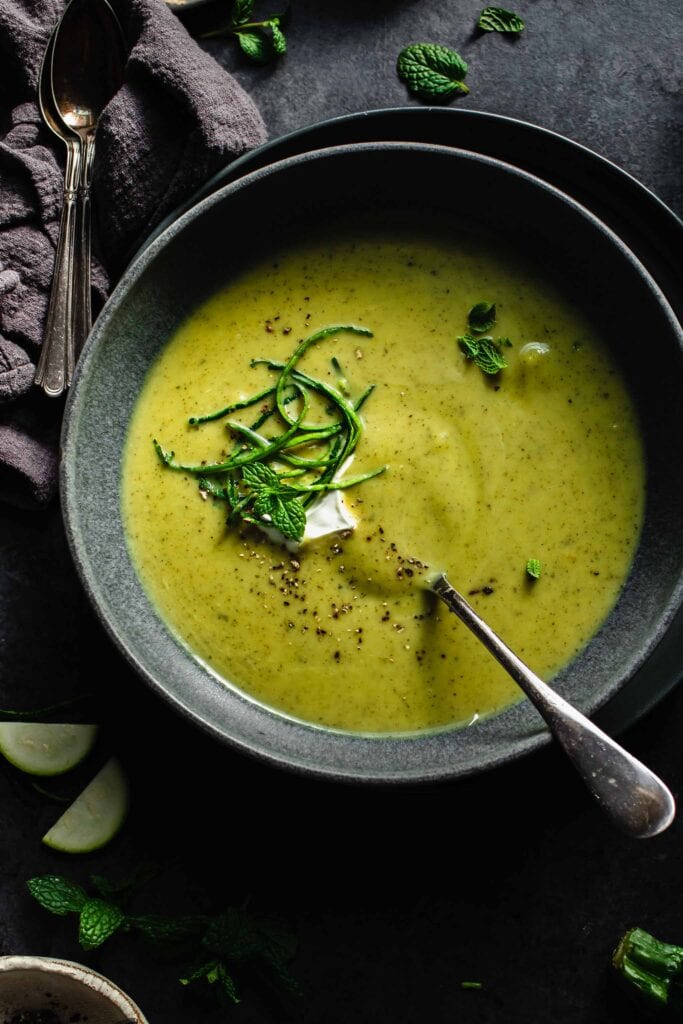Overhead shot of bowl of creamy zucchini soup with spoon.