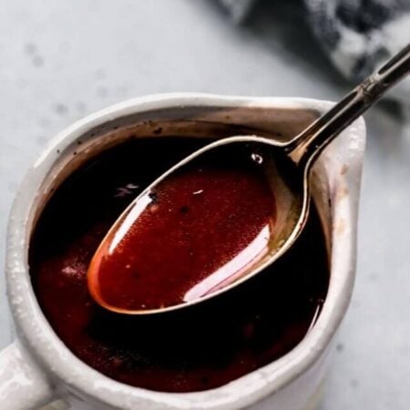 Red wine sauce in small serving container with spoon.