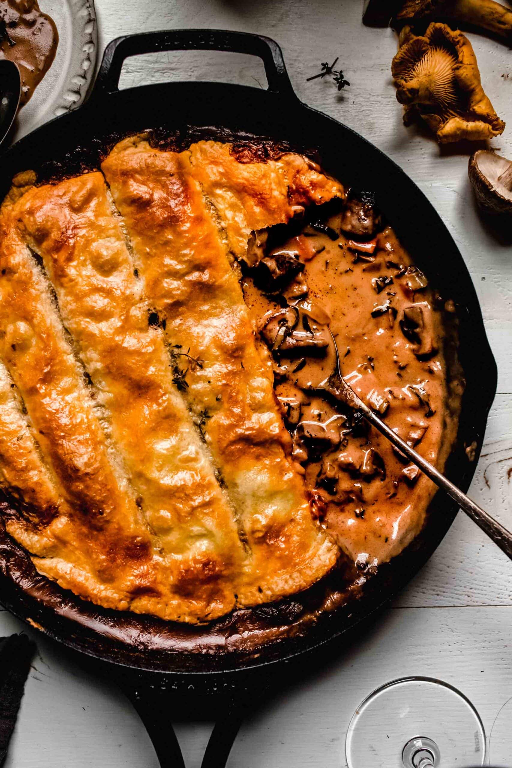 OVERHEAD SHOT OF MUSHROOM POT PIE IN SKILLET WITH SCOOP OUT OF IT.