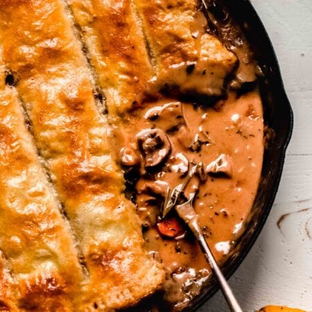 OVERHEAD SHOT OF MUSHROOM POT PIE IN SKILLET WITH SCOOP OUT OF IT.